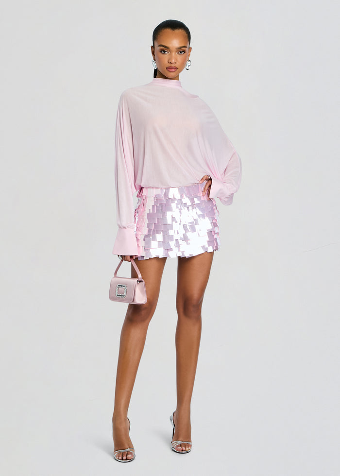 Model wearing Bennedetta Sequin Skirt ensemble with a soft pink draped top, pastel pink sequin mini skirt, and matching handbag. media 2 of 5