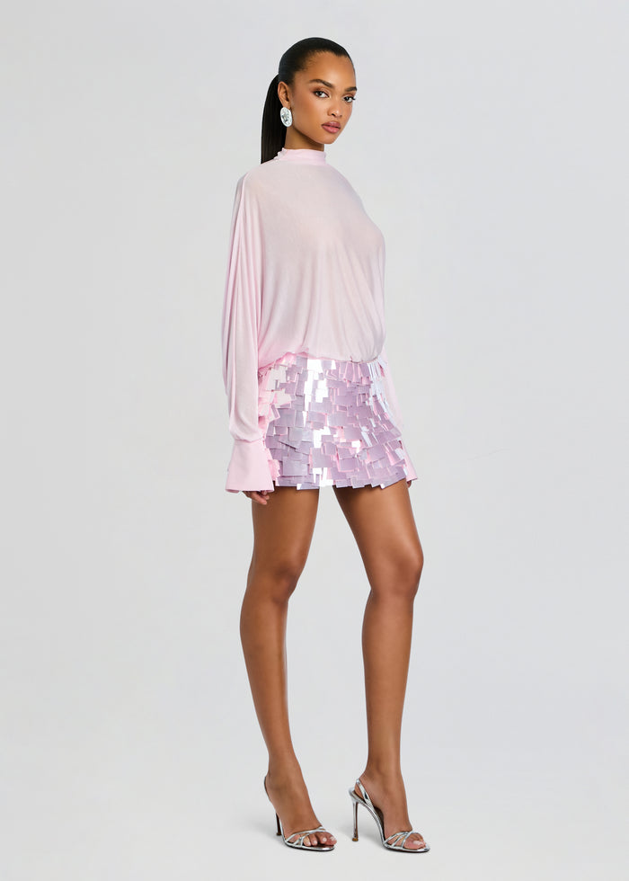 Model in Bennedetta Sequin Skirt look from the side wearing a pale pink top and lavender pink sequined mini skirt with silver heels. media 4 of 5