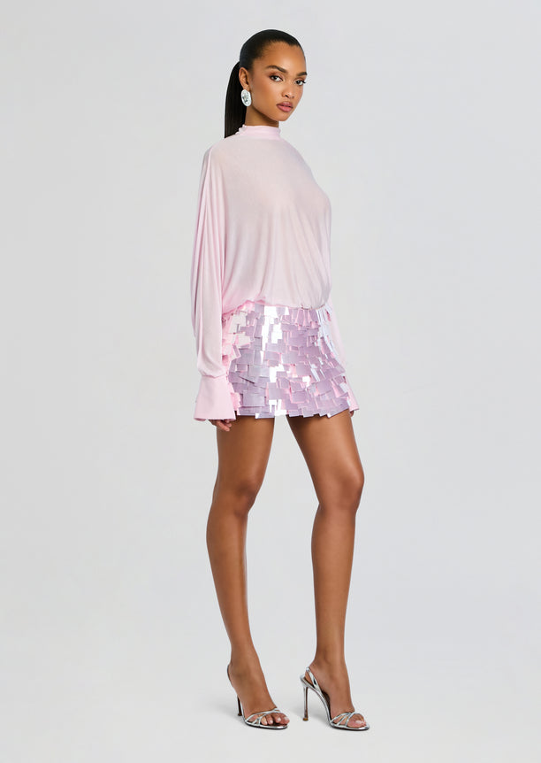 Model in Bennedetta Sequin Skirt look from the side wearing a pale pink top and lavender pink sequined mini skirt with silver heels.