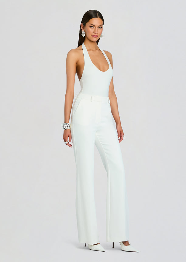 Full length model wearing white Eira Pant with halter neck top and statement earrings