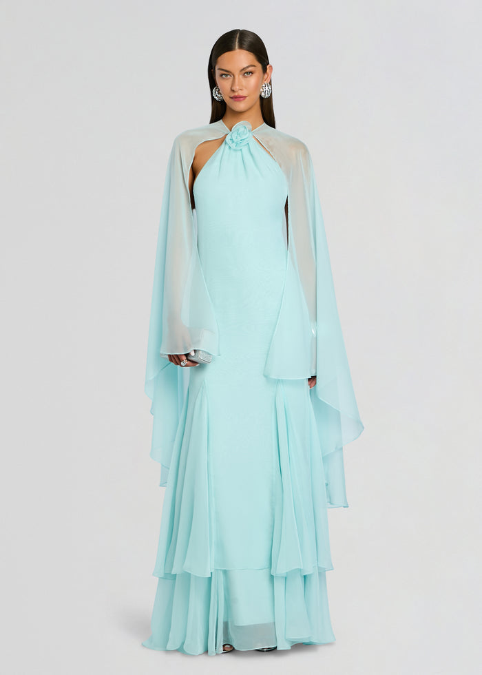 Full-length view of a model in a pale blue Lirael Chiffon Dress with a draped cape and layered hem. media 1 of 5