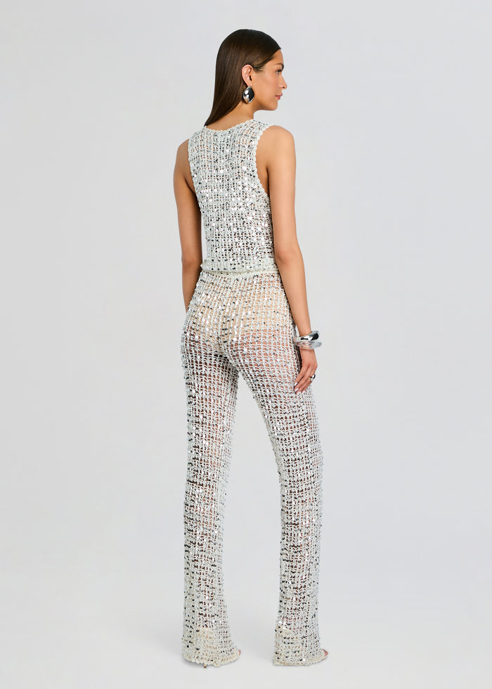 Back view of Nirvana Sequin Crochet Jumpsuit on model showing sleeveless silver crochet top and wide sequined pants media 4 of 5