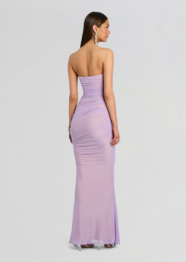 Back view of a model in Quintessa Mesh Dress lavender with a strapless bodice and crocheted mesh panels at the waist and a sheer hem.