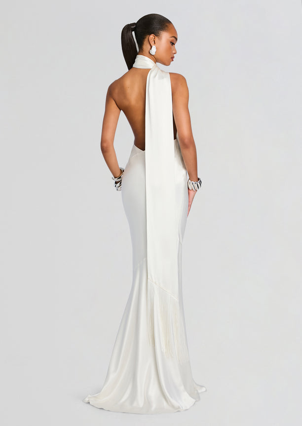 Back view of a white Kelsa Dress with halter neckline and long draped back scarf, satin gown with fringe at the hem.