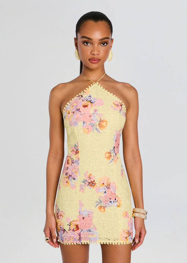 Front view of a model wearing the Kysha Short Dress in pale yellow with pink and purple floral print and a halter neckline