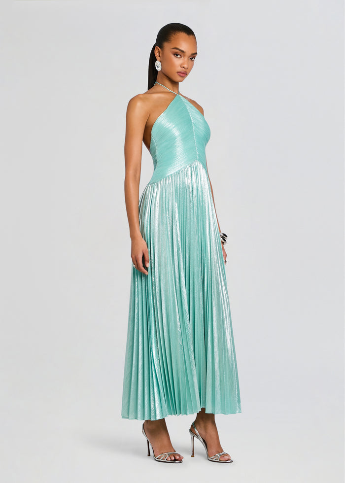 Full-length model wearing the turquoise Ivee Dress with a halter neckline and metallic pleated skirt media 3 of 5