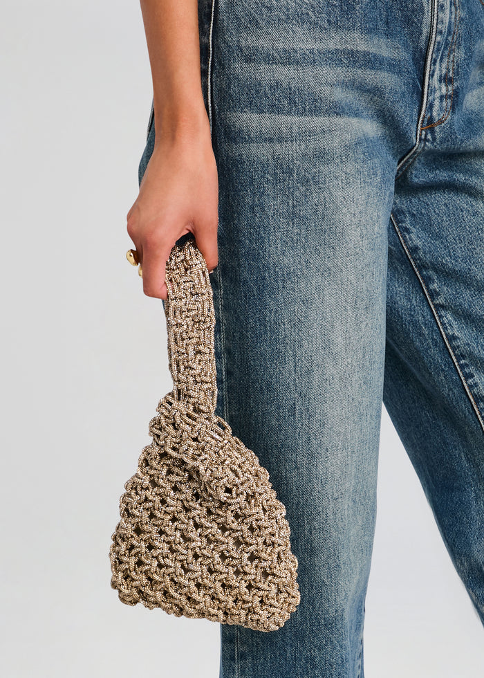Niky Bag in beige beaded crochet style held by a hand against blue denim jeans media 2 of 4