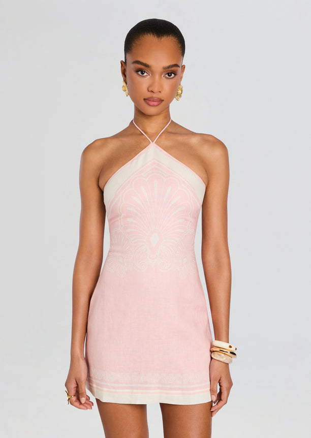 Front view of a model wearing a pale pink linen mini dress with a halter neckline and delicate white pattern
