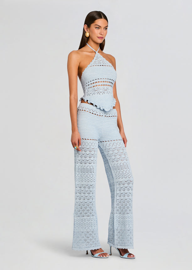 Model wearing light blue crochet halter top and matching high-waisted wide-leg pants with openwork lace details.
