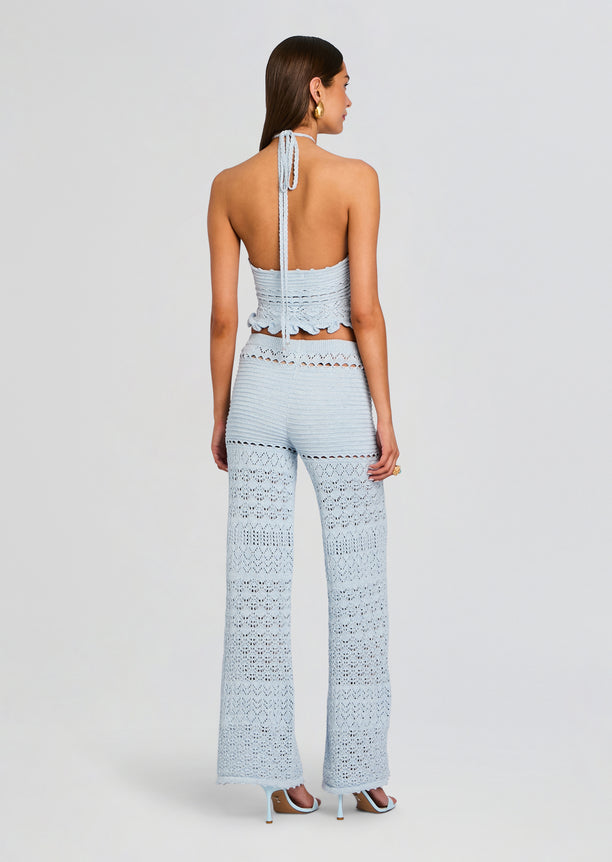 Back view of model in pale blue crochet halter top and matching wide-leg pants with scalloped details.
