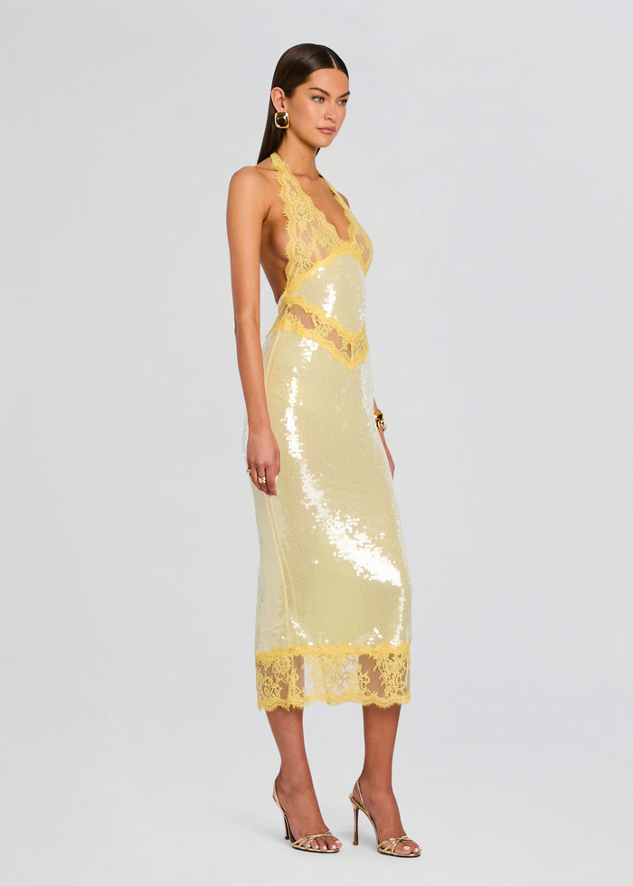 Side view of model in Vicky Sequin Lace Dress showing yellow lace halter and gold sequin midi silhouette with lace hem. media 4 of 6