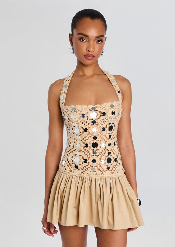 Beige crochet halter dress with large circular motifs and a short flared skirt on a model
