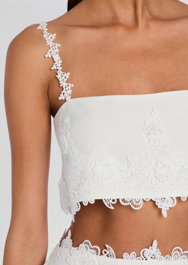 Close-up of white Dextra Top showing a floral lace strap and scalloped edge.