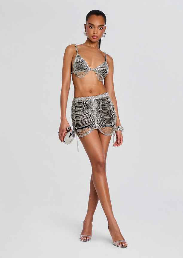 Model in Sylvio Chain Skirt ensemble featuring a jeweled chain bra and draped silver chain mini skirt.