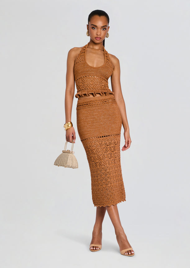 Front view of a model wearing the Leony Crochet Skirt two piece set in tan, featuring a halter top and matching lace crochet midi skirt, with a woven handbag.