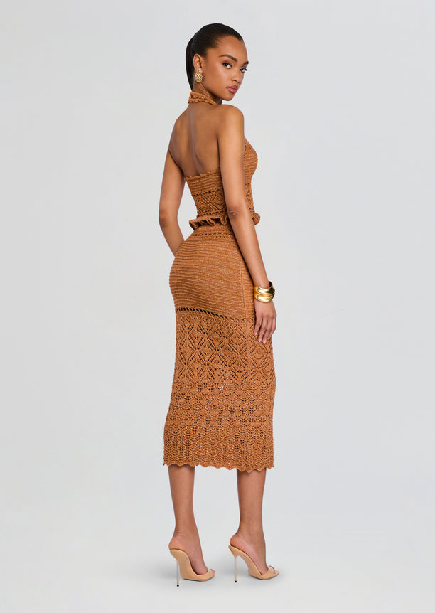 Back view of a model wearing the Leony Crochet Skirt two piece set in tan, featuring a halter top and fitted crocheted midi skirt with scalloped hem.