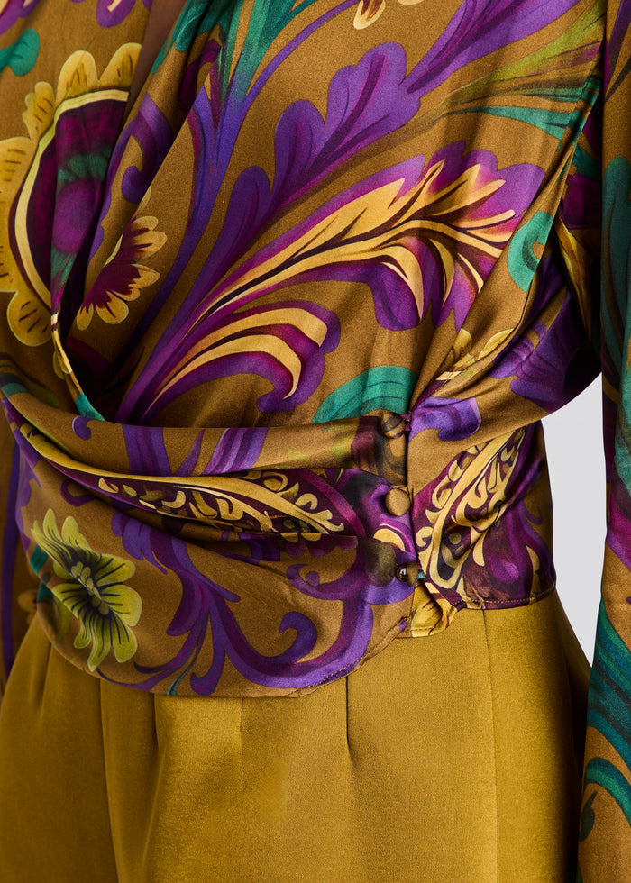 Close-up of a draped garment with a richly patterned print in purple, gold, teal, and green, tied at the waist over a solid mustard yellow skirt or bottom panel. media 3 of 5