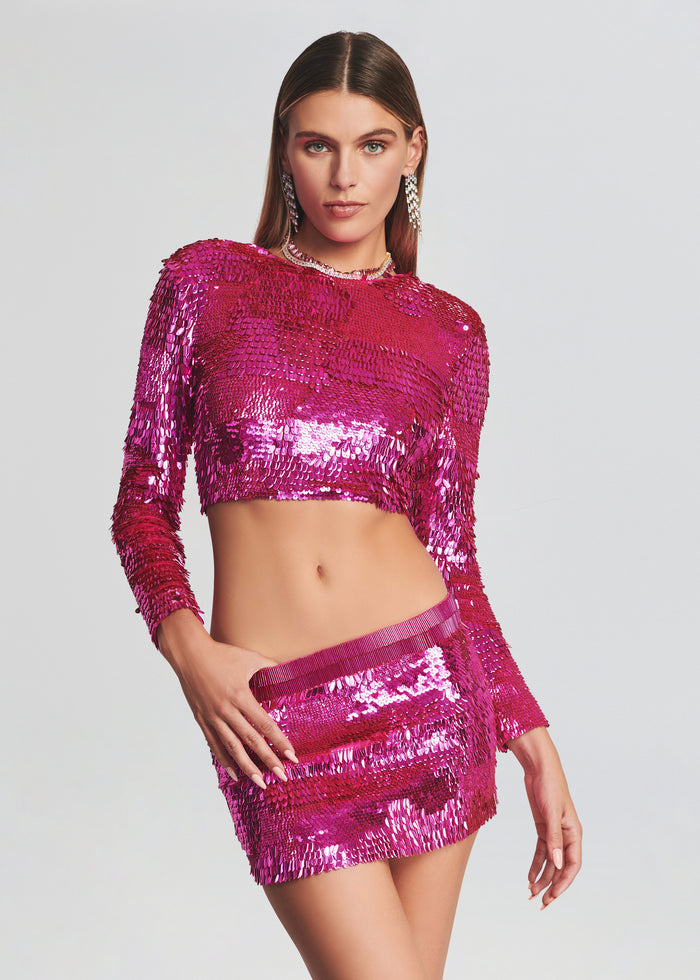 Front view of model wearing magenta sequin cropped top and matching mini skirt with statement earrings. media 4 of 4