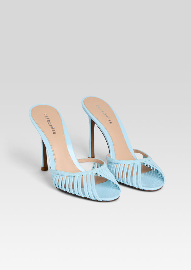 Pair of light blue strappy high heel sandals with thin heels on a white background.