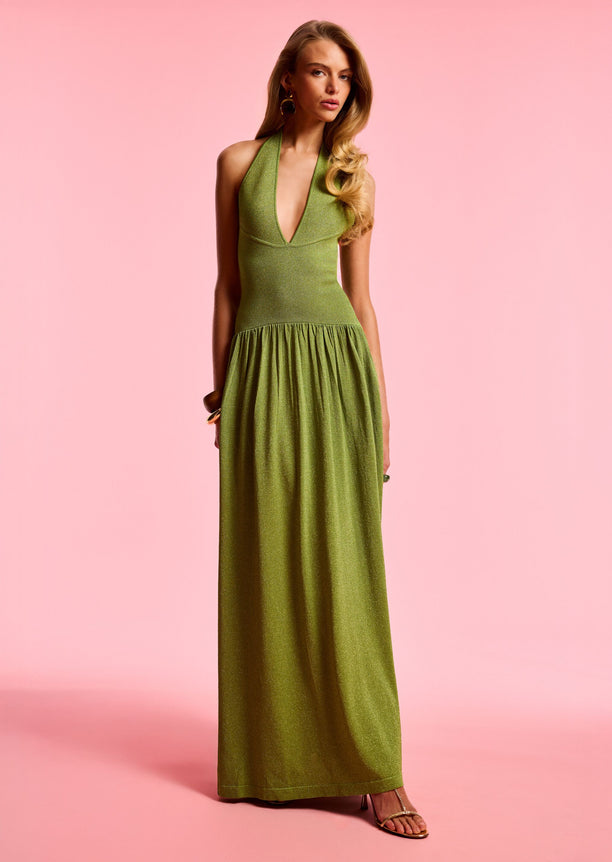 Marcelle Knit Dress in shimmering olive green, full length halter gown against a pink backdrop.