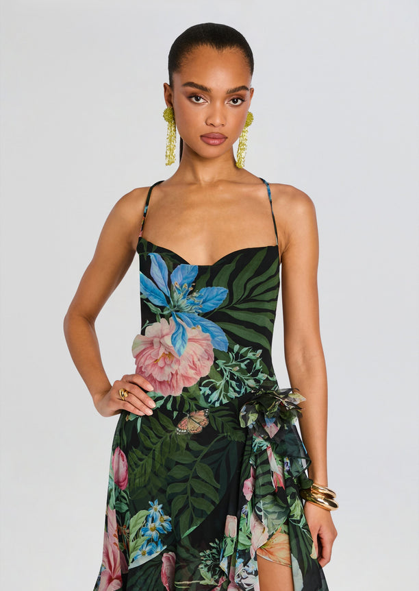 Front view of a model wearing a tropical floral silk chiffon dress with thin straps and a layered sheer wrap skirt.
