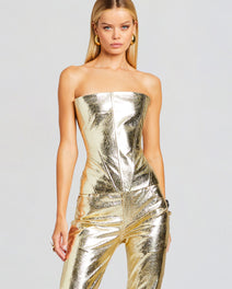 Model in a metallic gold strapless leather top with matching metallic pants and gold hoop earrings
