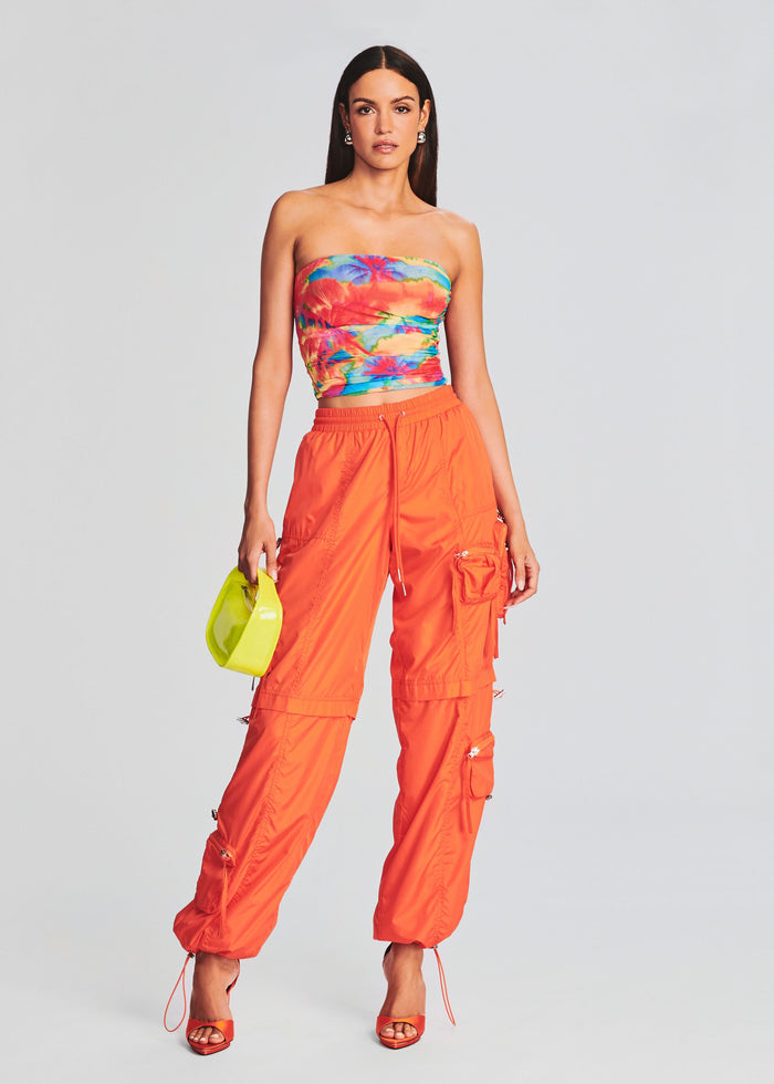 Model in a tropical print tube top with neon orange cargo pants and a lime clutch. media 2 of 5