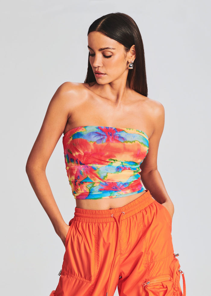 Model in a tropical print strapless tube top with bright orange cargo pants. media 1 of 5