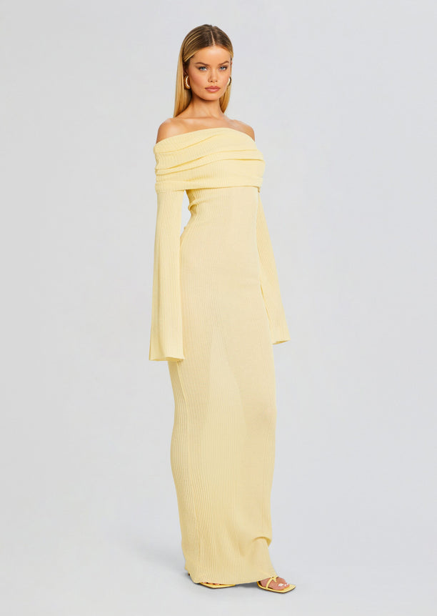 Full length view of a model in a pale yellow off-the-shoulder ribbed maxi dress with long sleeves.