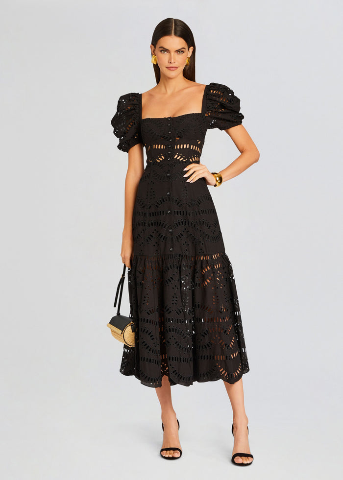 Front view of a model wearing a black Spiana Long Dress with puff sleeves and a perforated eyelet pattern. media 1 of 5