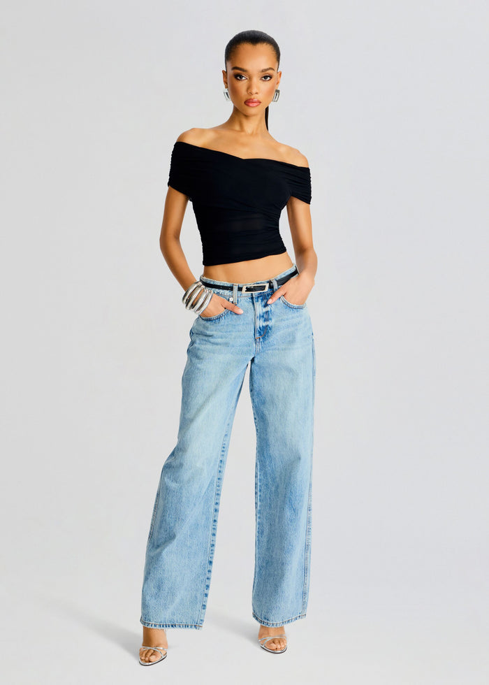 Model wearing Aruba Mesh Top black off shoulder crop top with light wash wide leg jeans and silver bracelets. media 2 of 5