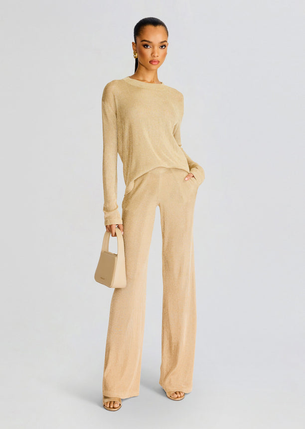 Full-length shot of model in Hana Metallic Knit Top with matching beige wide-leg pants and a small beige handbag.