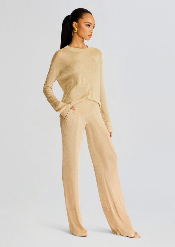 Side-profile of model wearing Hana Metallic Knit Top with matching beige pants and gold earrings.