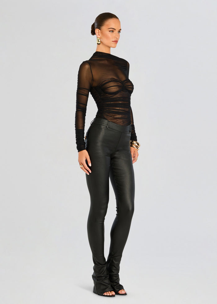 Full-length shot of a model wearing Mila Ruched Bodysuit with Asymmetric Neck in sheer black top paired with black leather pants media 3 of 5