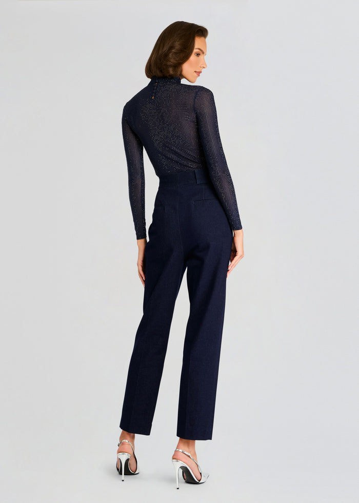 Back view of a model in the Bronwyn Embellished Top with sheer shimmering fabric, paired with navy tailored trousers and silver heels. media 4 of 5