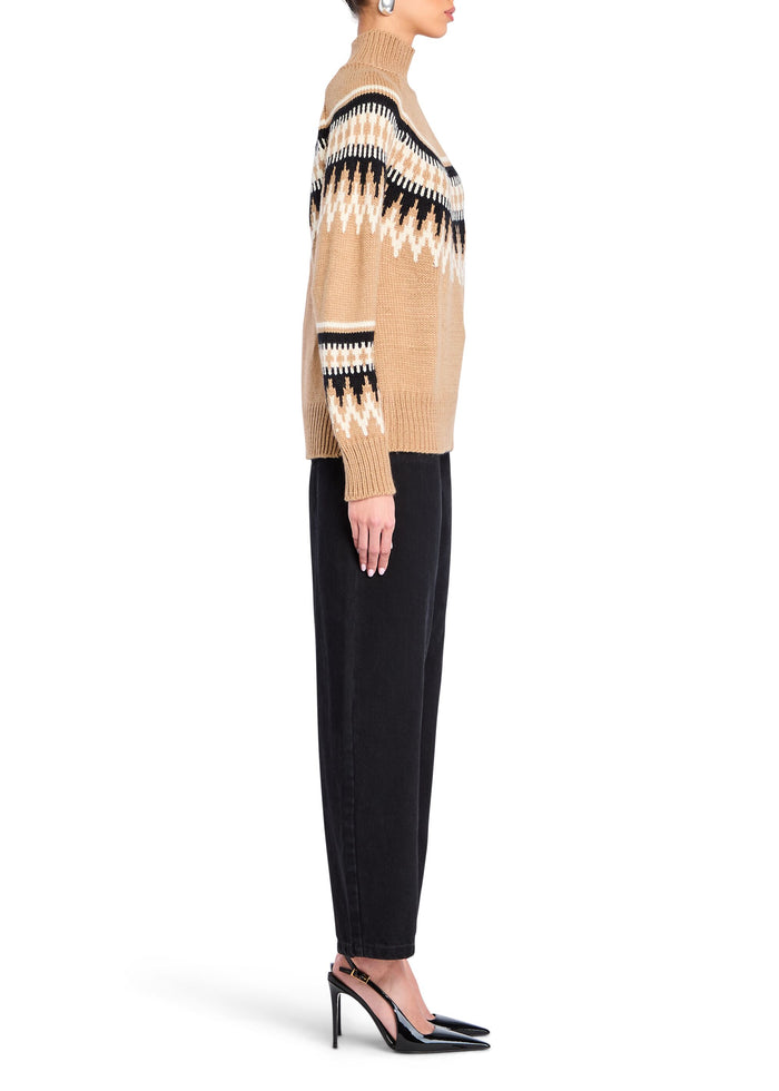 Side view of model wearing the beige Everest sweater with a geometric pattern paired with black trousers and heels. media 3 of 5