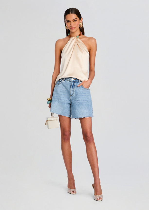 Model wearing Sabrina Boyfriend Short in light wash denim paired with a cream satin halter top