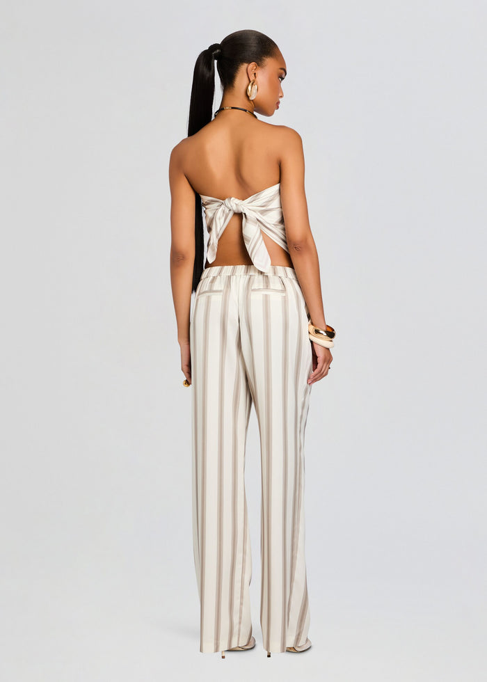 Back view of a model in a beige striped satin bandeau top tied in a bow at the back with matching striped pants. media 4 of 5