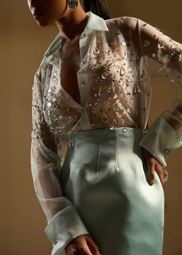 Close-up of the Eugenia Embellished Blouse with crystal droplets on sheer fabric, tucked into a mint-green high-waisted skirt media 2 of 6