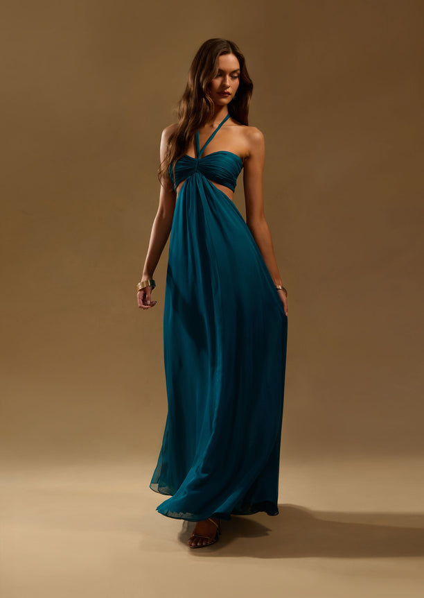 Teal Meira Chiffon dress on model with halter neckline and crossed straps leading to a flowing maxi skirt.