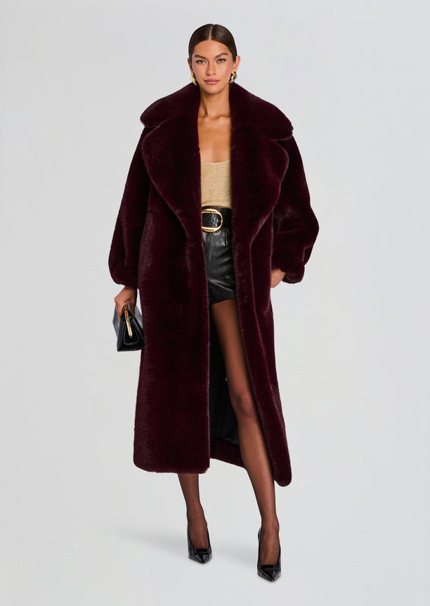 Model wearing a long burgundy Dasha faux fur jacket with a voluminous silhouette.