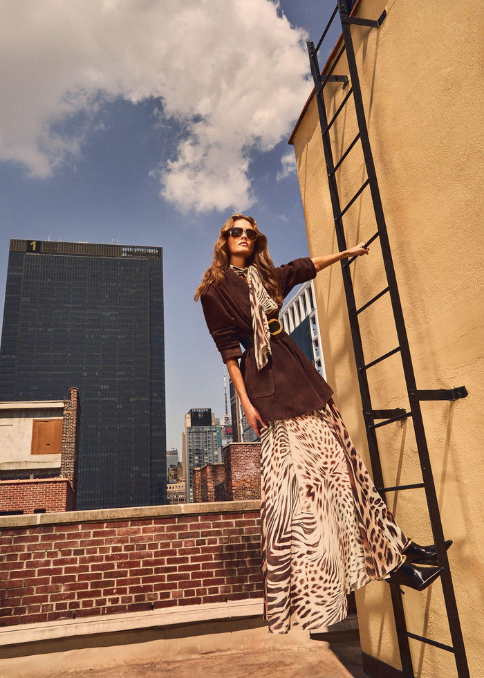 Model on a city rooftop wearing the Opaline Dress with a brown blazer and scarf against an urban skyline. media 2 of 6