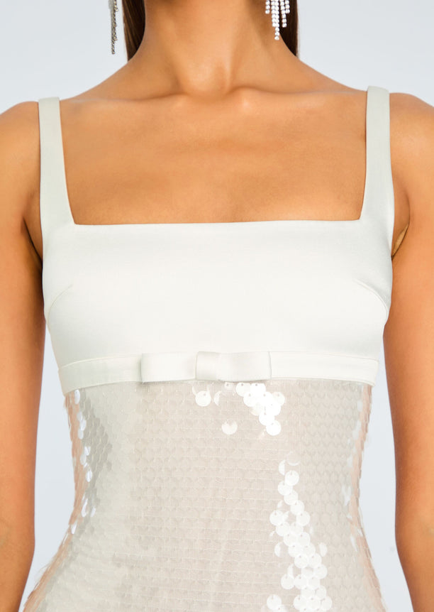 Close-up of the Yvaine Sequin Dress bodice showing a square neckline and wide straps over a pale sequined skirt.