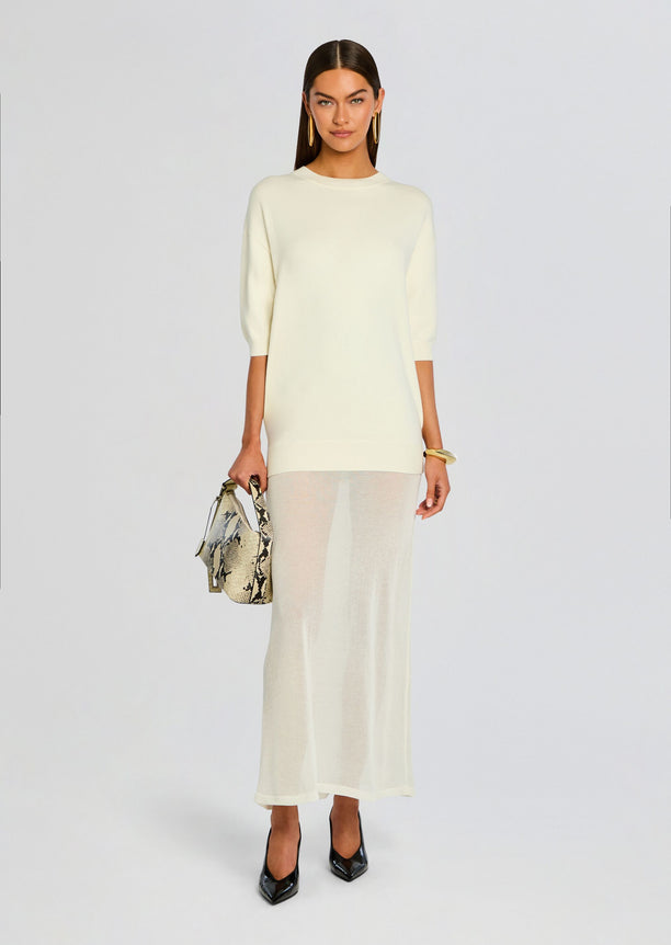 Cream knit maxi dress with three quarter sleeves worn by a model carrying a snakeskin handbag and wearing black heels