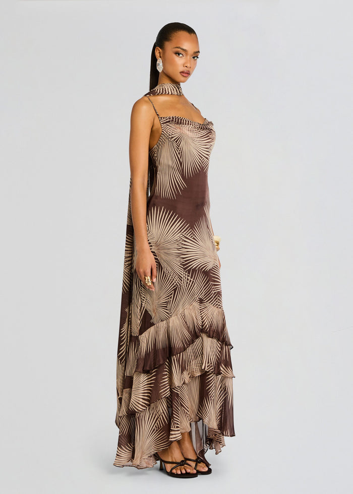 Model wearing brown palm leaf print maxi dress with a matching neck scarf and a layered ruffled hem media 4 of 5