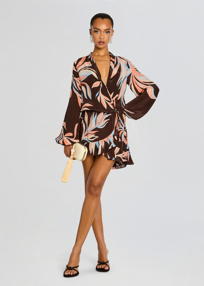 Model in brown tropical print wrap mini dress with deep V neck and belted waist. media 1 of 5