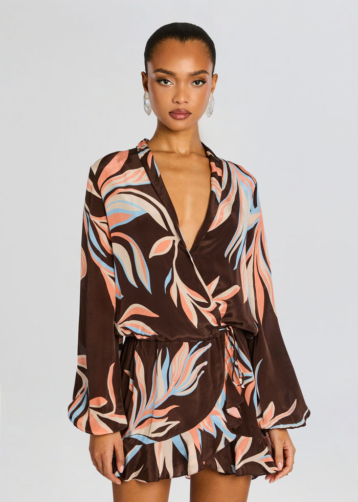 Model wearing Fern Front Wrap Mini Dress featuring brown leaf print, plunging V neckline, wrap front, tied waist, and a short ruffled hem. media 5 of 5