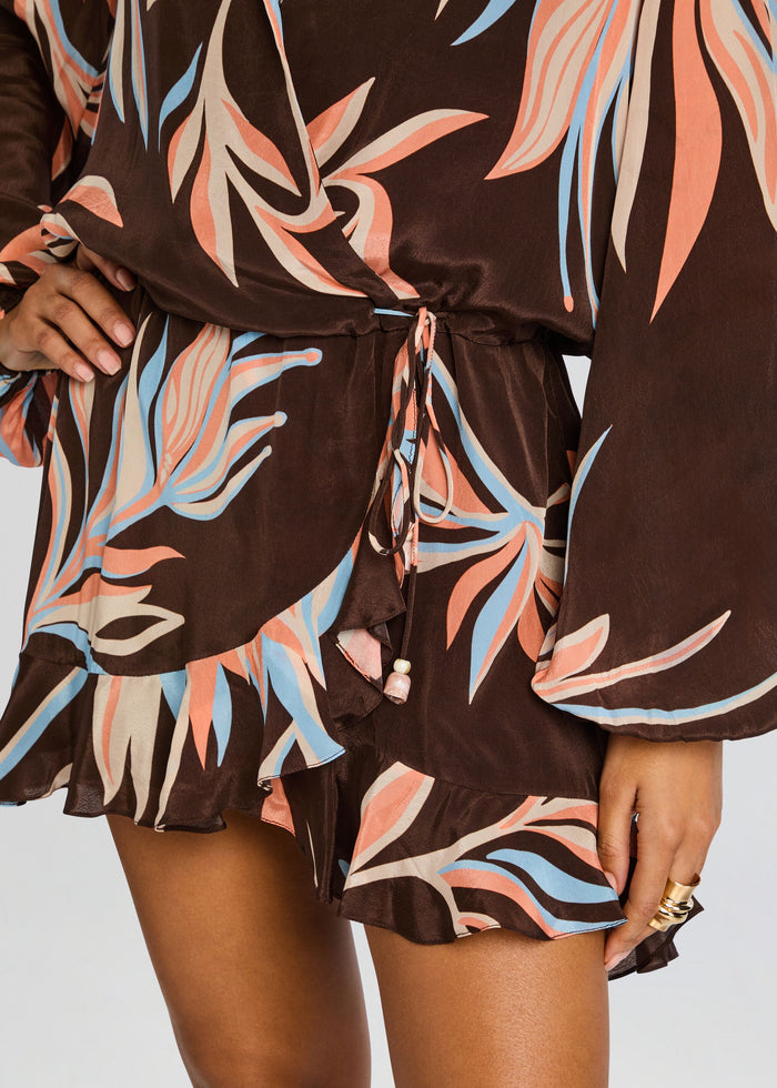 Close-up of the brown tropical print wrap dress showing belt tie and ruffled hem. media 2 of 5
