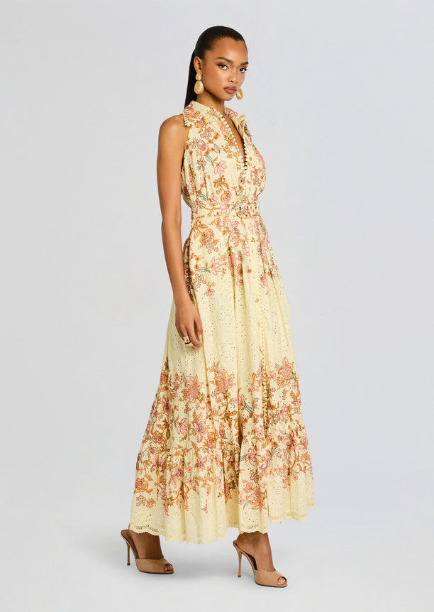Side view of a model wearing the Riah Long Dress with a belted waist and nude heels