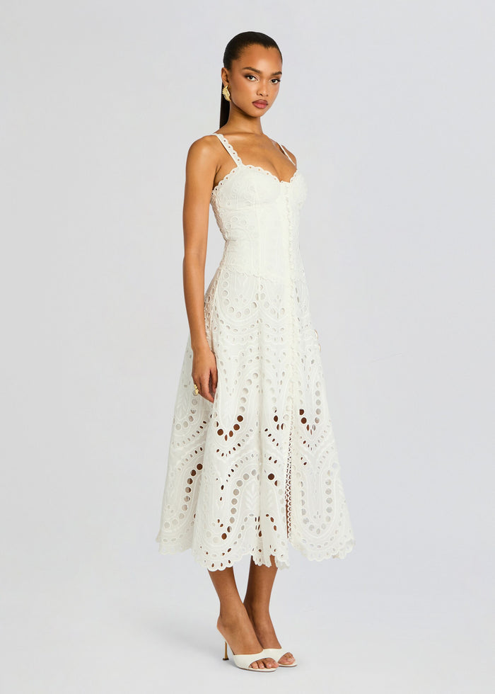 Model wearing ivory Solace Long Dress with intricate eyelet embroidery and scalloped hem, paired with white heels. media 3 of 5